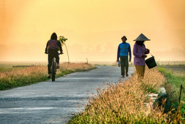 Mâini care curăță lanțul unei biciclete cu o perie, cu bicicleta sprijinită pe un stand de reparații
