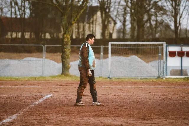 Jucători pe un teren de fotbal ud, cu minge și noroi